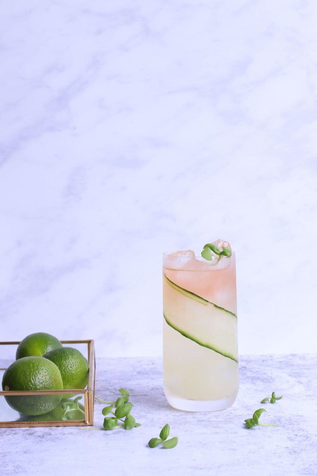 Mocktail élégant garni (concombre, herbes, glaçons) sur fond clair